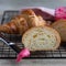 Fresh crispy croissants with pink honey on black metal grille, concrete background