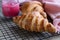 Fresh crispy croissants with pink honey on black metal grille, concrete background