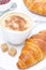 Fresh croissant, cappuccino and jam for breakfast, close-up