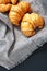 Fresh croissants on creased of gray linen placed on black background, vertical image.