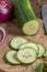 Fresh cucumbers, partly sliced, on chopping board with knife