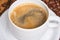 Fresh cup of coffee surrounded by coffee beans on a wooden background