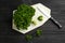 Fresh curly parsley, cutting board and knife on black wooden table, flat lay