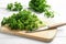 Fresh curly parsley, cutting board and knife on white wooden table