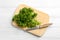 Fresh curly parsley, cutting board and knife on white wooden table, top view