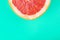Fresh cut grapefruit closeup on pastel green wall background.