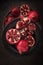 Fresh cuted pomegranates on the black plate on dark rustic background flat lay. 2