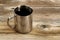 Fresh dark coffee in stainless steel cup on rustic wood