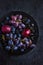 Fresh dark fruits and berries on black background.