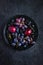 Fresh dark fruits and berries on black background.