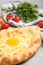 Fresh delicious Adjarian khachapuri on light table, closeup