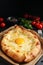 Fresh delicious Adjarian khachapuri served on black table, closeup