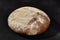 Fresh, delicious baked round bread sprinkled with flour. Black background with copy space. Rural cuisine or bakery