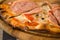 Fresh delicious crunchy thin crust pizza lies on wooden stand closeup