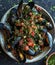 Fresh and delicious mussels cooked with tomato, parsley on a ceramic bowl