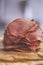Fresh and delicious stack of sliced pastrami meat placed on wooden cutting board