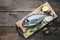 Fresh dorado fish with lemon slices,  sea salt and rosemary twigs on wooden cutting board. Top view.