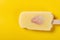 a fresh durian flavor popsicle with slice of strawberry on a yellow background