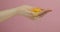 Fresh egg on the woman hand. Manicure hand holds egg yolk on pink background