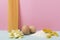 Fresh eggs, heap of flour for dought and different types of pasta on the blue surface against pink background