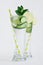 Fresh elegant detox cocktail of cucumber, lime, mint, straw with bubbles, drops on soft white wooden backgrounds.