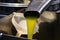 Fresh extra virgin olive oil pouring into tank at a cold-press factory