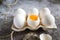Fresh farm white chicken eggs close up, one broken, visible yolk 1