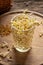 Fresh fenugreek sprouts in a glass with dry seeds in the background