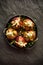 Fresh figs stuffed with gorgonzola cheese, pine nuts, honey and herbs in a black dish on a dark, stone background, top view.