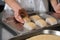 Fresh fish fillet cube covered in breadcrumbs, being placed onto a metal baking tray