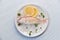 Fresh fish on plate ice with lemon and parsley white table background top view