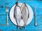 Fresh fish on the plate, table setting, wooden background