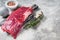 Fresh Flank or flap raw beef steak on wooden board with herbs. Gray background. Top view. Copy space