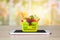 Fresh food and vegetables in green shopping basket on mobile smartphone on wood table