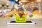 Fresh food and vegetables in shopping basket on mobile smartphone on wood table with supermarket aisle blurred background