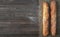 Fresh French baguette made from white flour cools after baking. Bread located on burlap, rustic dark wooden background. Top view,