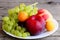 Fresh fruits assortment. Grapes bunch, peach, plum, apricot on a white plate and a wooden background. Closeup