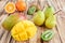 Fresh fruits of mango and mango cubes, pears, orange, kiwis on wooden background