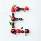 Fresh fruits pattern of letter E english alphabet from natural ripe berries - black currant, cherries, raspberry, mint