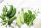 Fresh garden organic green vegetables - cucumbers, zucchini, chard, green peas, onions, cauliflower on a light background, top vie