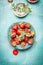 Fresh garden Strawberries in bowl and strainer with powdered sugar on turquoise blue background