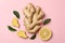 Fresh ginger, leaves and lemon on pink background