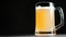 Fresh gold light beer with white fluffy foam slowly rotation isolated at black studio background