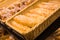 Fresh golden breads with melted cheese wrapped in plastic wrap in wicker basket in bread department of supermarket