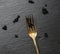 Fresh grainy black paddlefish caviar in metal fork on a black background