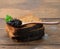 Fresh grainy black paddlefish caviar and slices of bread in brown wooden spoon on a brown table, close up