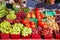 Fresh grapes, tomatoes, groundcherries displayed in containers on an outdoor market stall