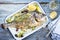 Fresh Greek barbecue gilthead seabream with peperoni and Kalamata olives in a white skillet