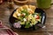 Fresh Greek salad on black plate with pita tomato feta cheese cucumber and onion on wooden table