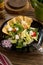 Fresh Greek salad on black plate with pita tomato feta cheese cucumber and onion on wooden table